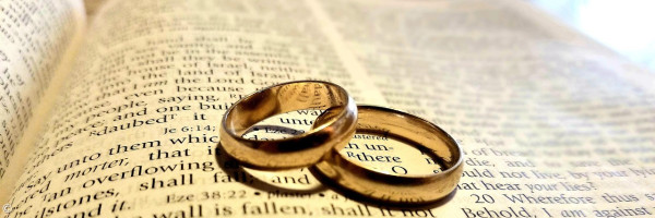 Zwei Eheringe auf einer Bibel liegend